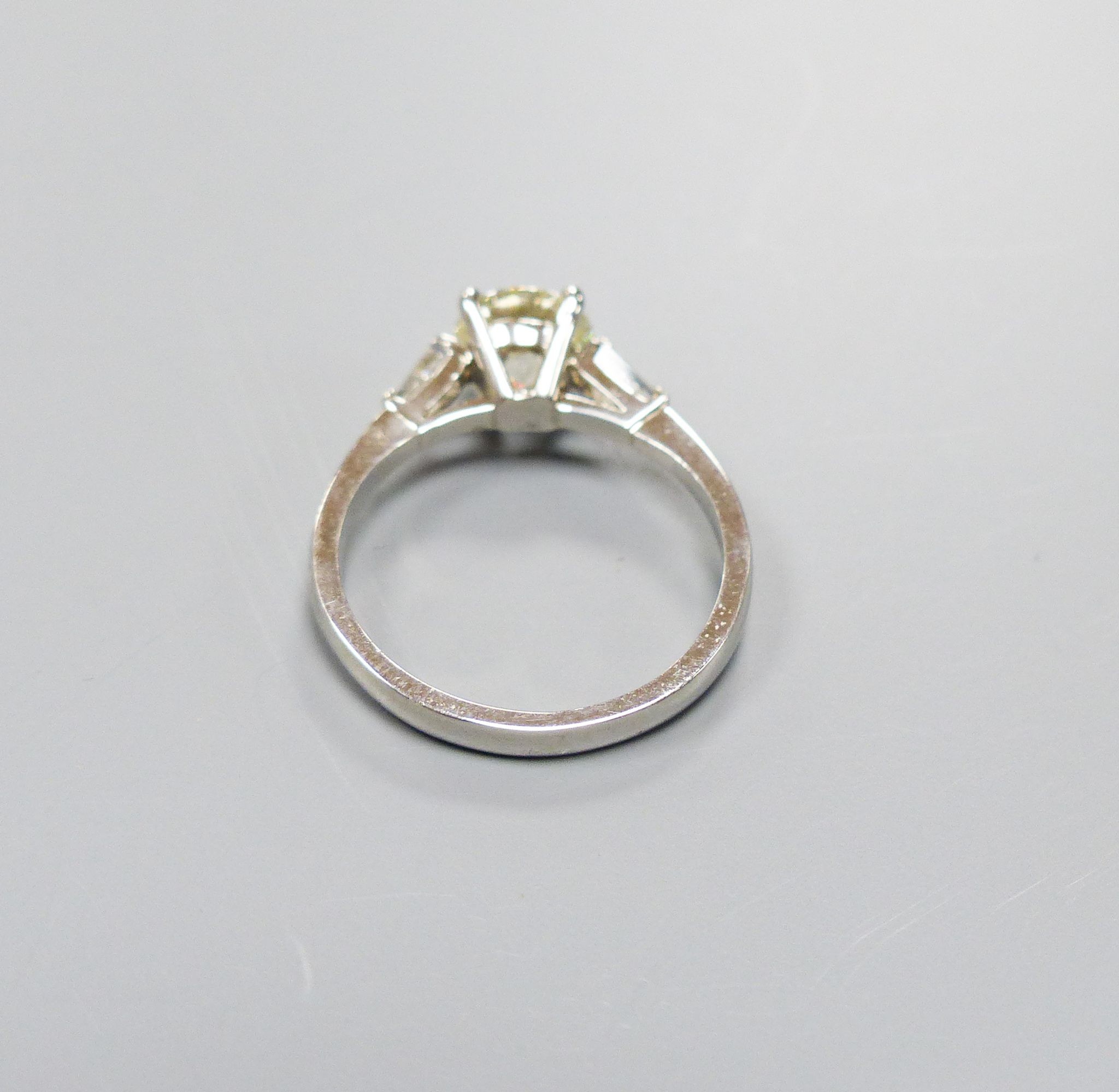 A modern platinum and single stone diamond ring, with trapeze cut diamond set shoulders, size O, gross weight 4.3 grams